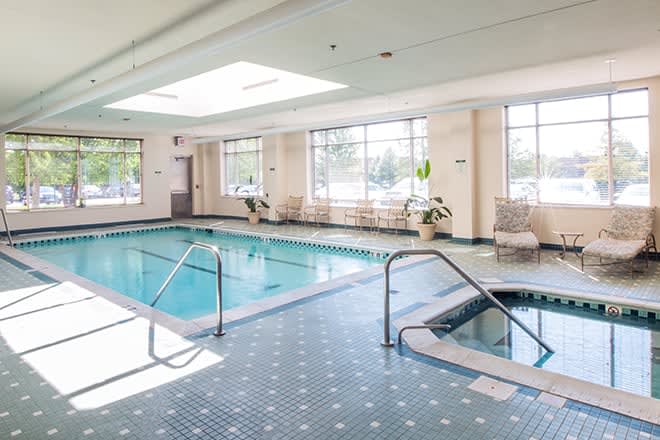 A serene indoor swimming area featuring a pool and jacuzzi, bathed in natural light.