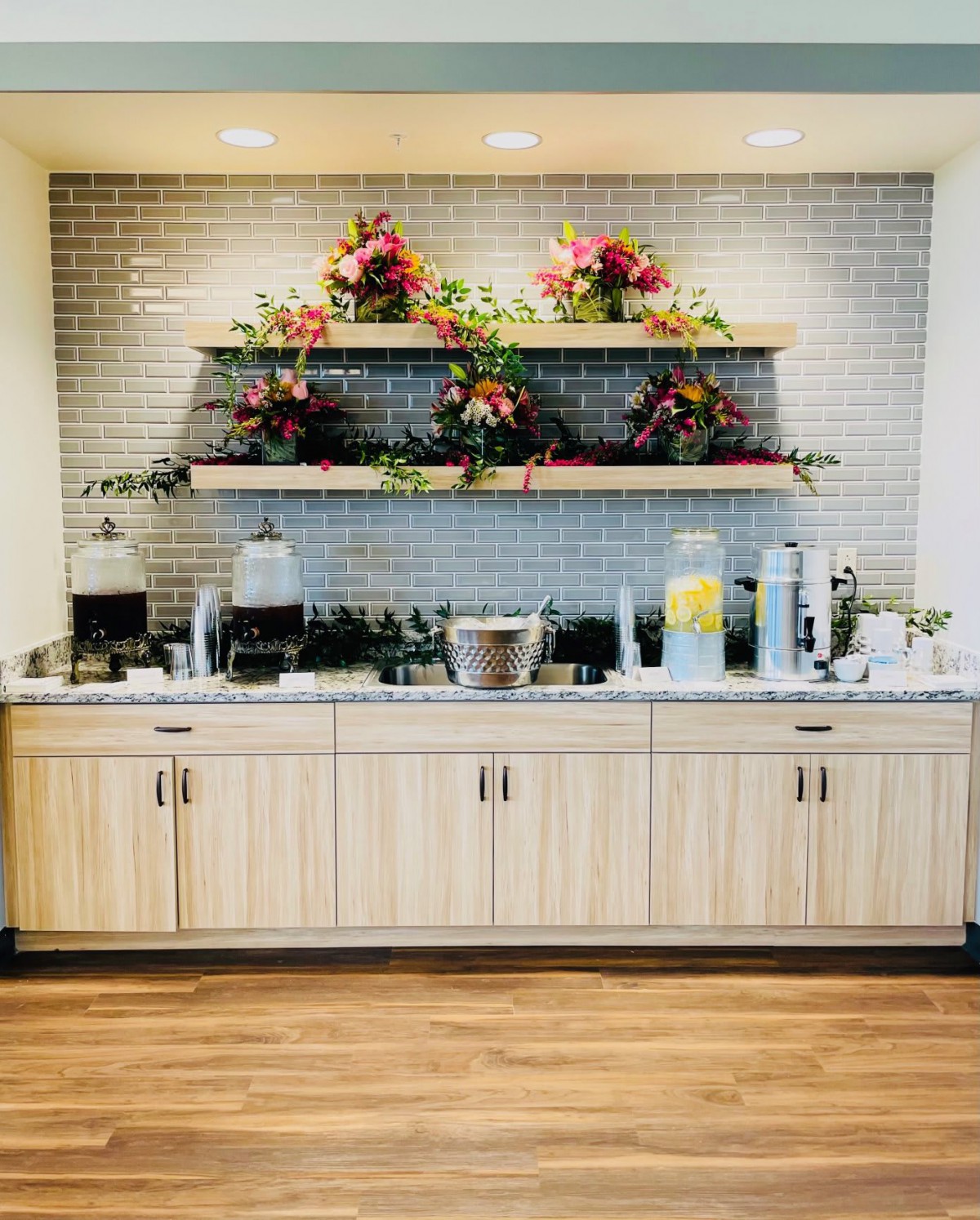 A well-organized beverage and coffee station with floral decorations and various drink options.