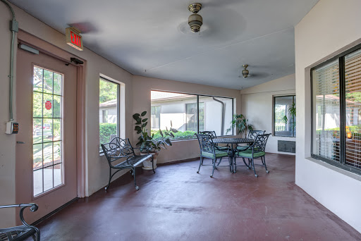 A serene indoor patio area featuring tables and chairs, adorned with plants and illuminated by natural light.
