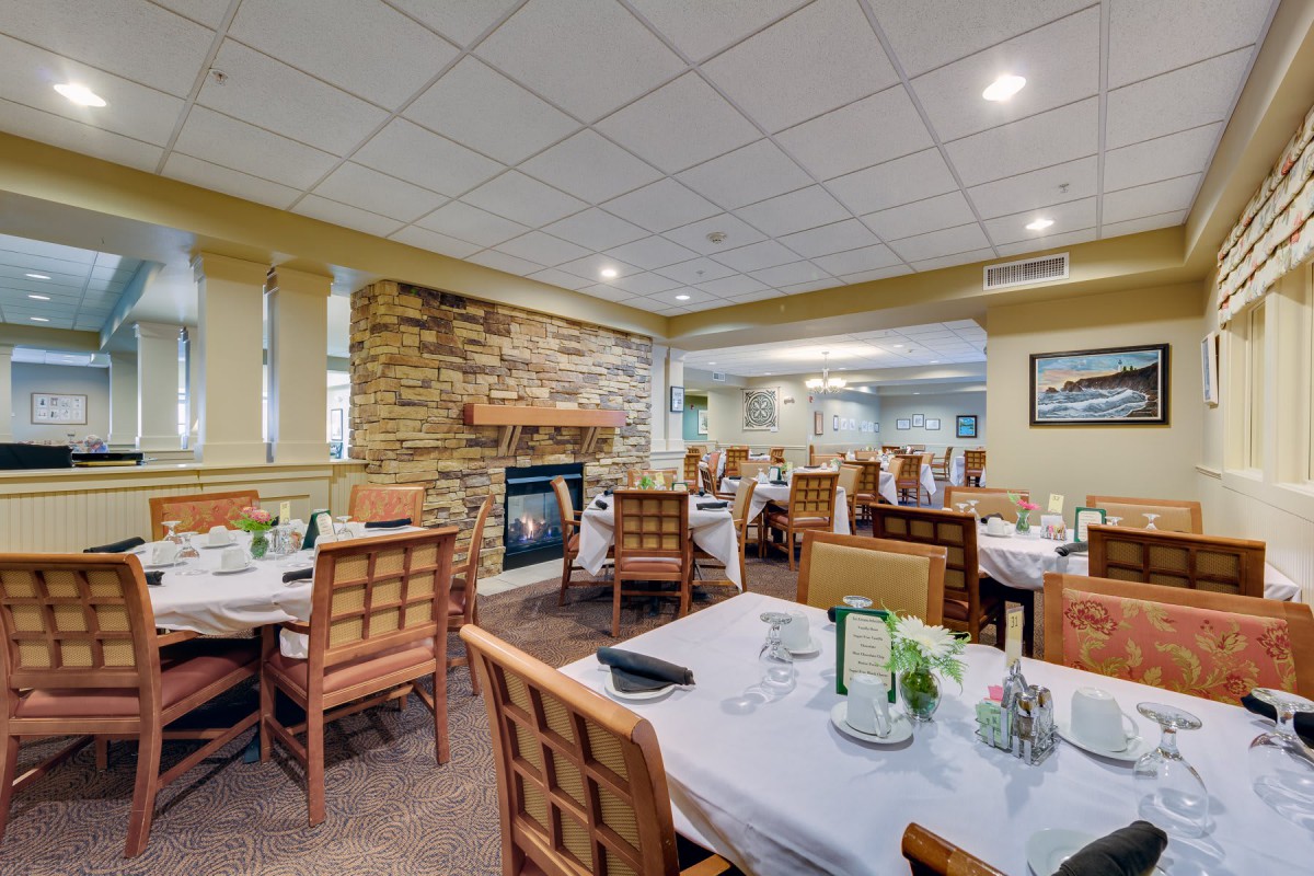 A cozy restaurant dining area with neatly arranged tables and a stone fireplace.