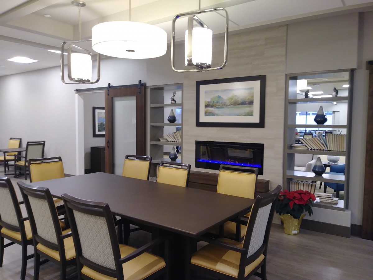 A modern dining room with a large table, surrounded by chairs and adorned with contemporary lighting and wall art.