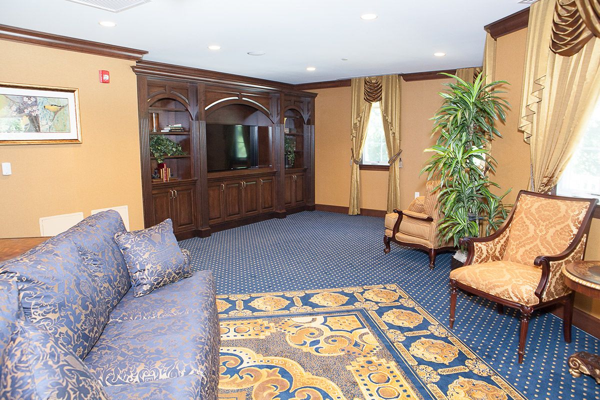 A cozy living room featuring a large wooden cabinet, patterned carpet, and comfortable seating.