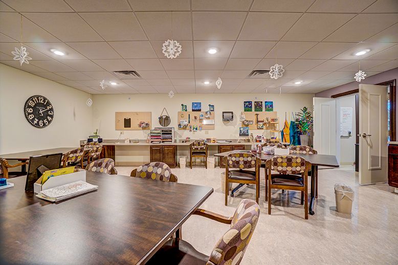 A well-equipped classroom or meeting space with tables, chairs, and various art supplies.