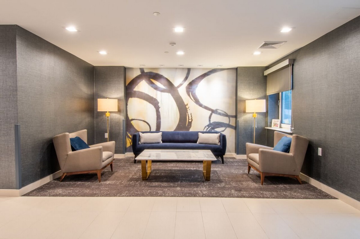 A modern living room featuring a stylish sofa, two chairs, and a coffee table, with contemporary artwork on the wall.