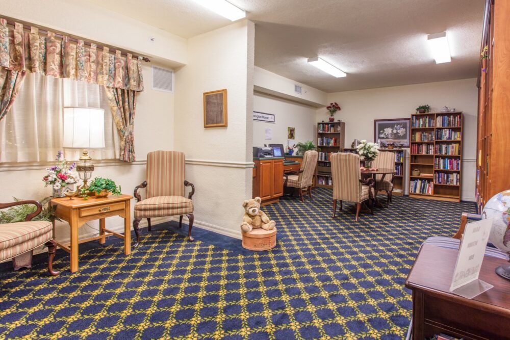A cozy living room with patterned carpet, armchairs, and bookshelves.