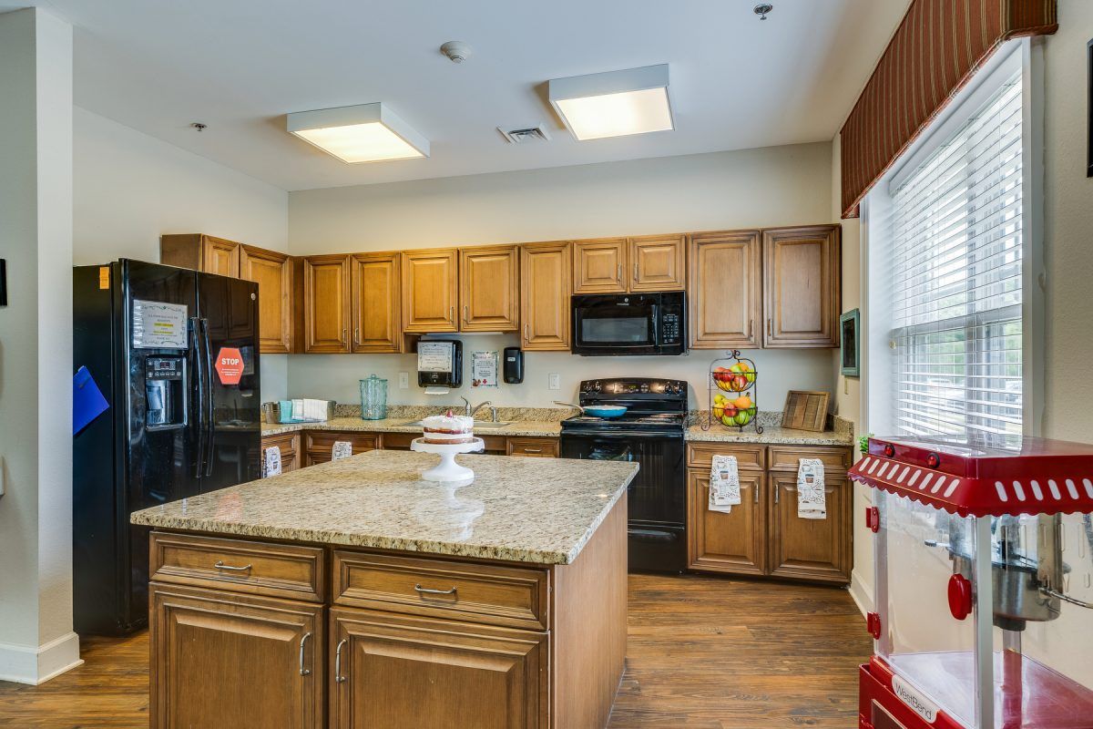 A modern kitchen with wooden cabinets and an island, featuring appliances and bright lighting.