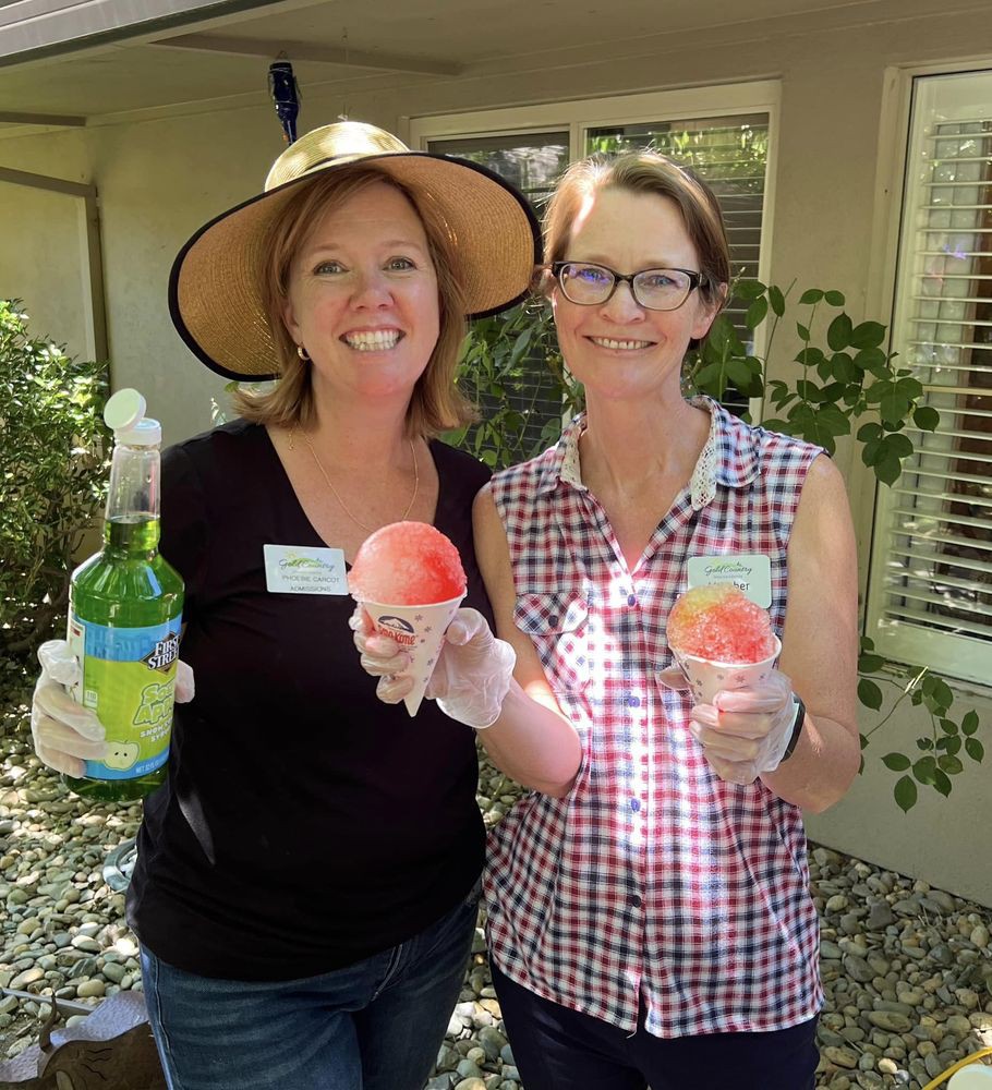 Two women smiling outdoors, holding drinks.