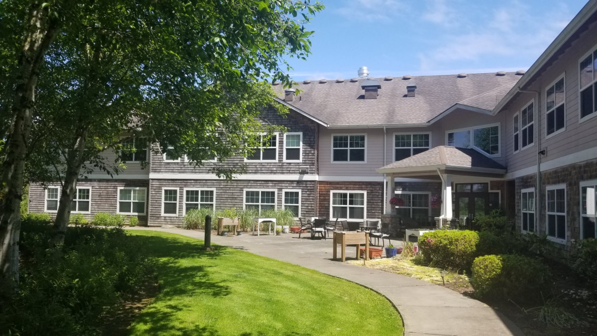 A two-story building with a well-maintained lawn and outdoor seating area.
