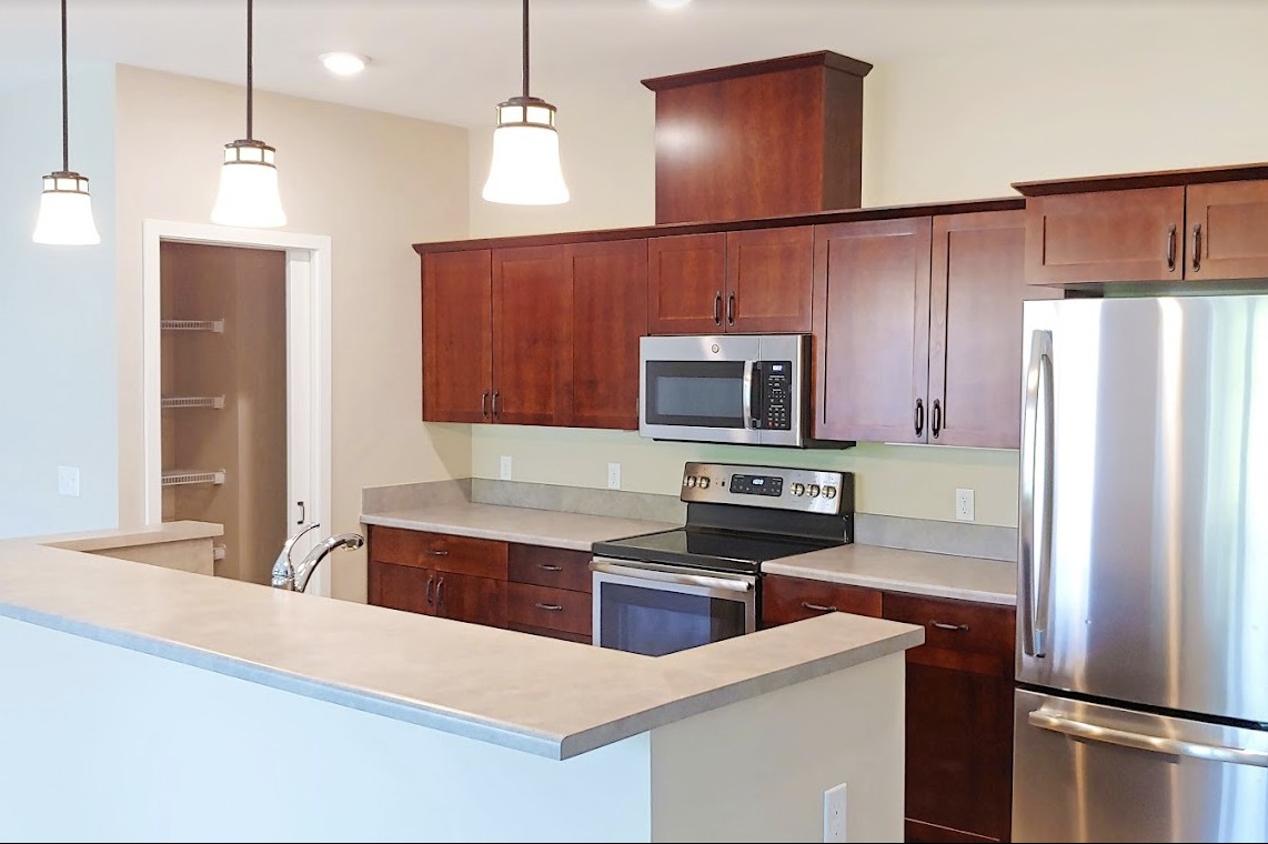 Modern kitchen with dark wood cabinets and stainless steel appliances.