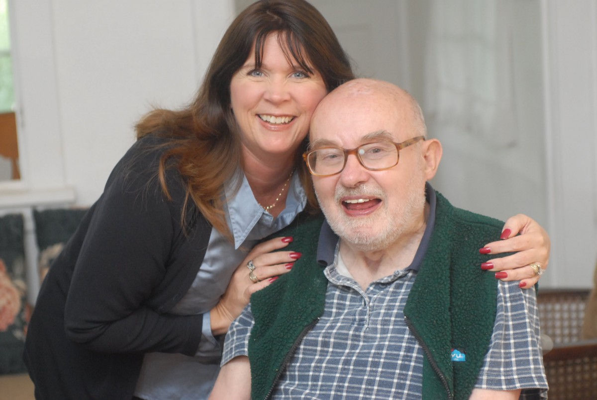A woman smiling with an elderly man indoors.