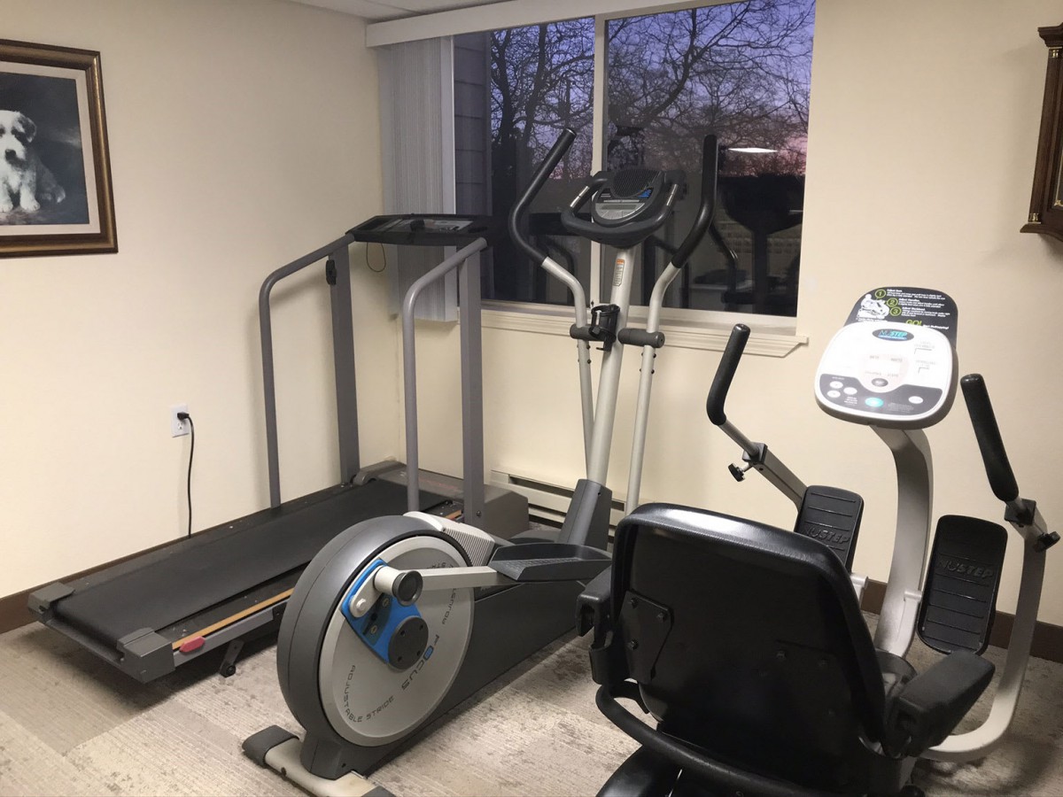 A small indoor gym with a treadmill, exercise bike, and elliptical machine.