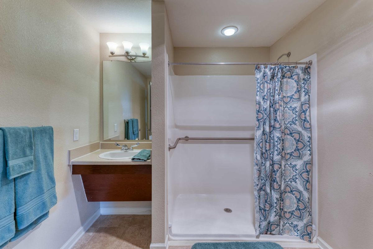 A modern bathroom with a shower area and a sink with a mirror.