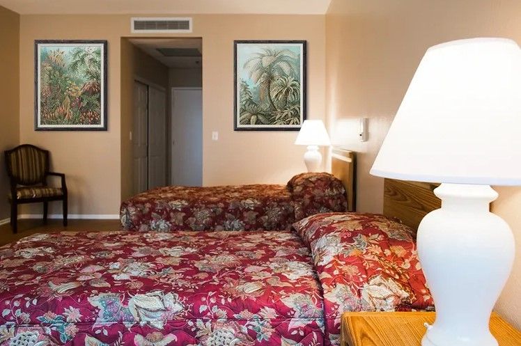 A cozy hotel room with two beds featuring floral bedding and decorative paintings on the wall.
