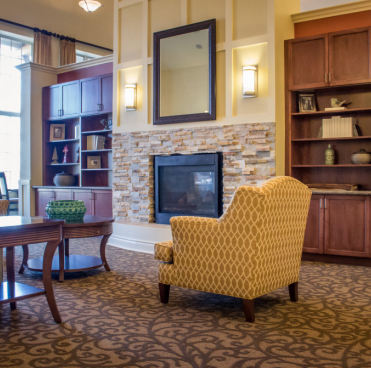 A cozy living room with a fireplace and comfortable armchair surrounded by bookshelves.