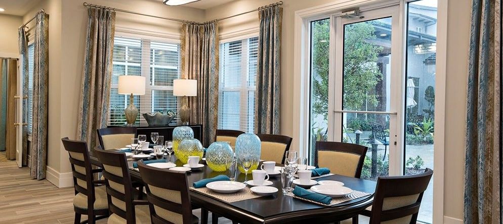 A modern dining room with an elegantly set table, featuring blue glass pitchers and neatly arranged napkins.