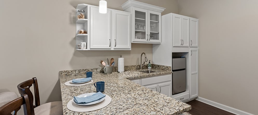 A modern kitchen featuring granite countertops and white cabinets, complete with stainless steel appliances and minimalist decor.