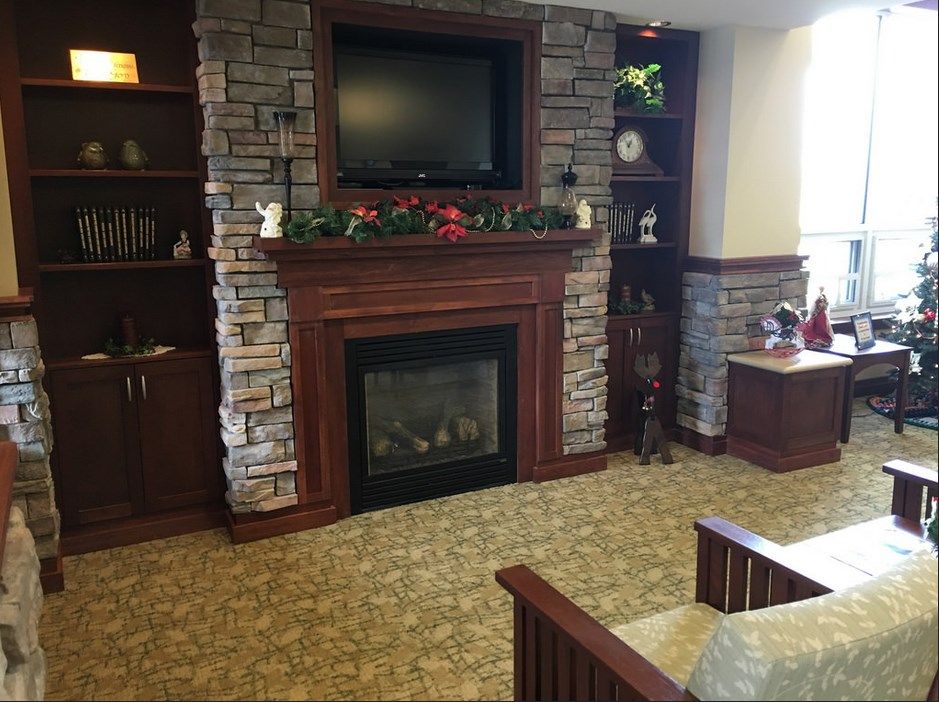 A cozy living room with a stone fireplace and television, decorated with plants and stylish furniture.