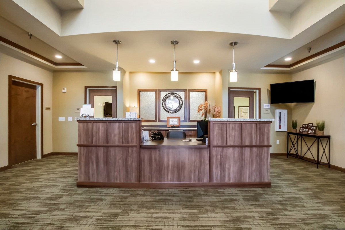 A modern office reception area with a wooden desk and elegant lighting.