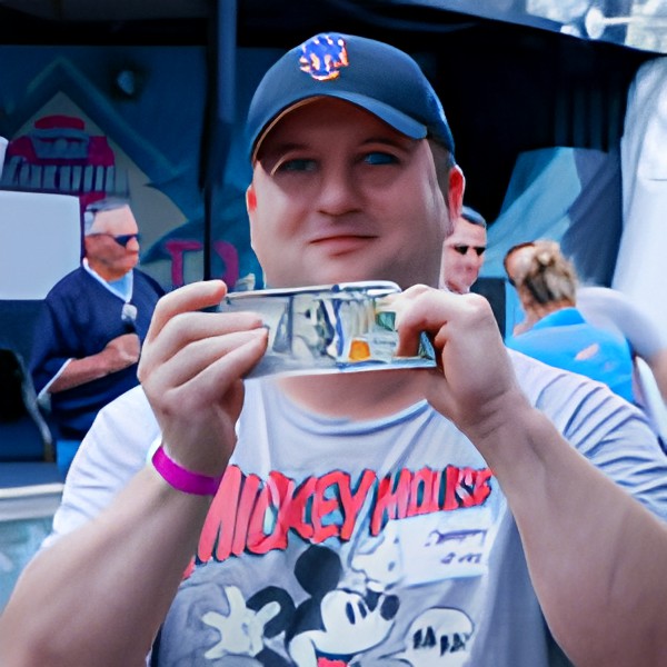 A man wearing a NASA cap and Mickey Mouse shirt holds up a stack of money at an outdoor event.