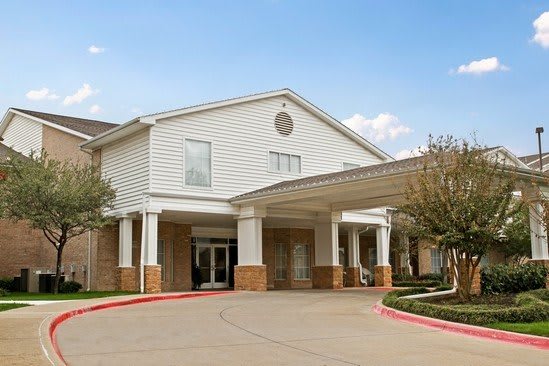 The image shows the entrance of a large residential building with a covered driveway.