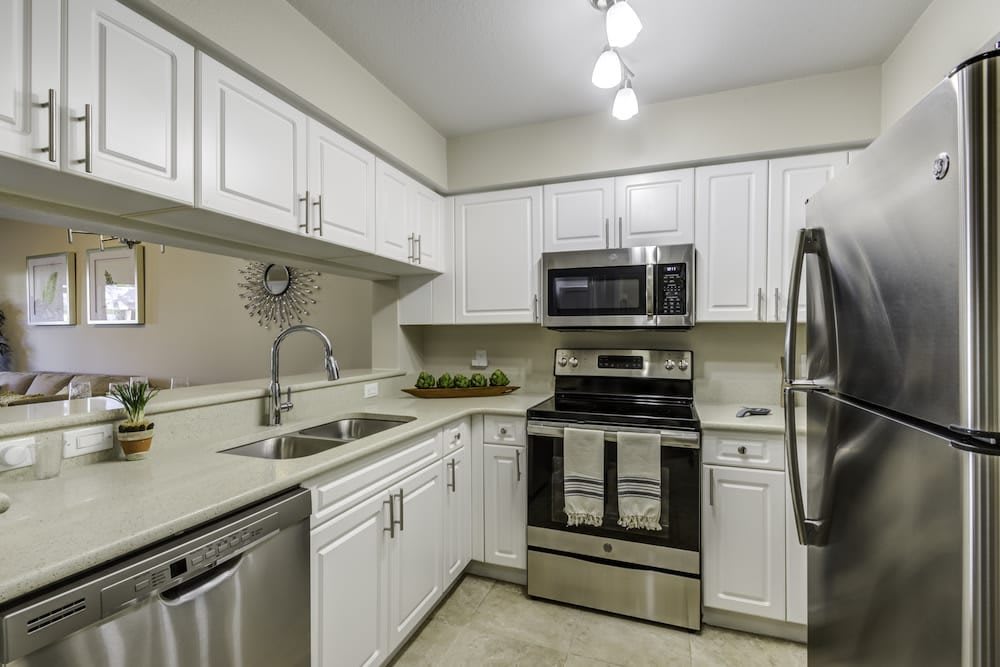 Modern kitchen with white cabinets and stainless steel appliances.