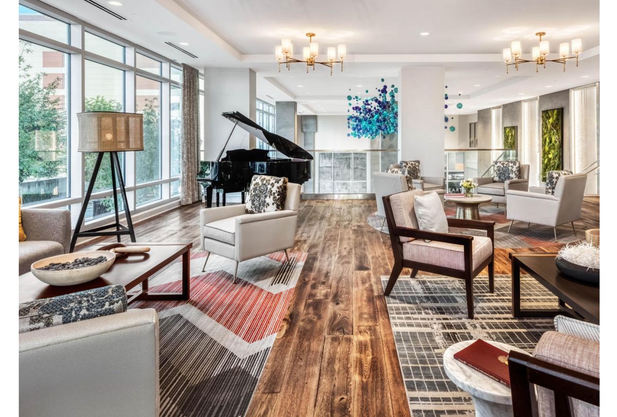 A modern living room with a grand piano, stylish furniture, and ample natural light from large windows.