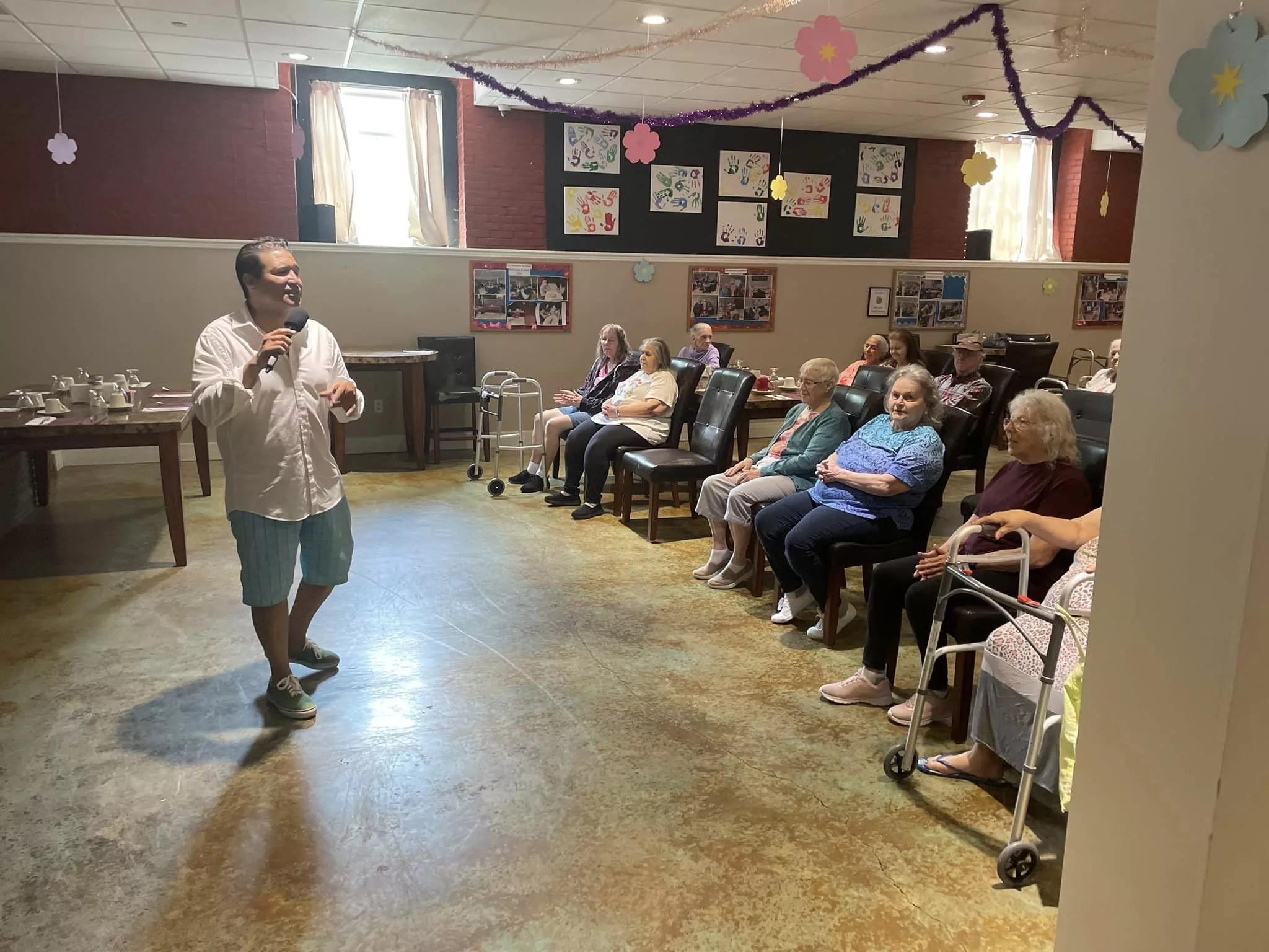 A person giving a presentation to a group of elderly individuals in a community center.
