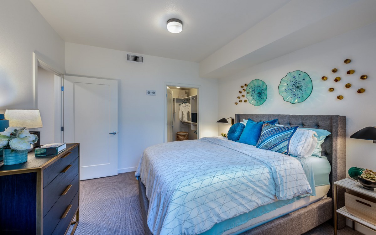 A modern bedroom with stylish decor, featuring a neatly made bed and decorative wall art.
