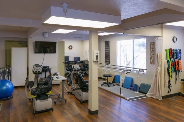 A rehabilitation room with exercise equipment and parallel bars for physical therapy.