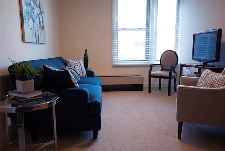 A cozy living room with a sofa, chairs, and a large window.