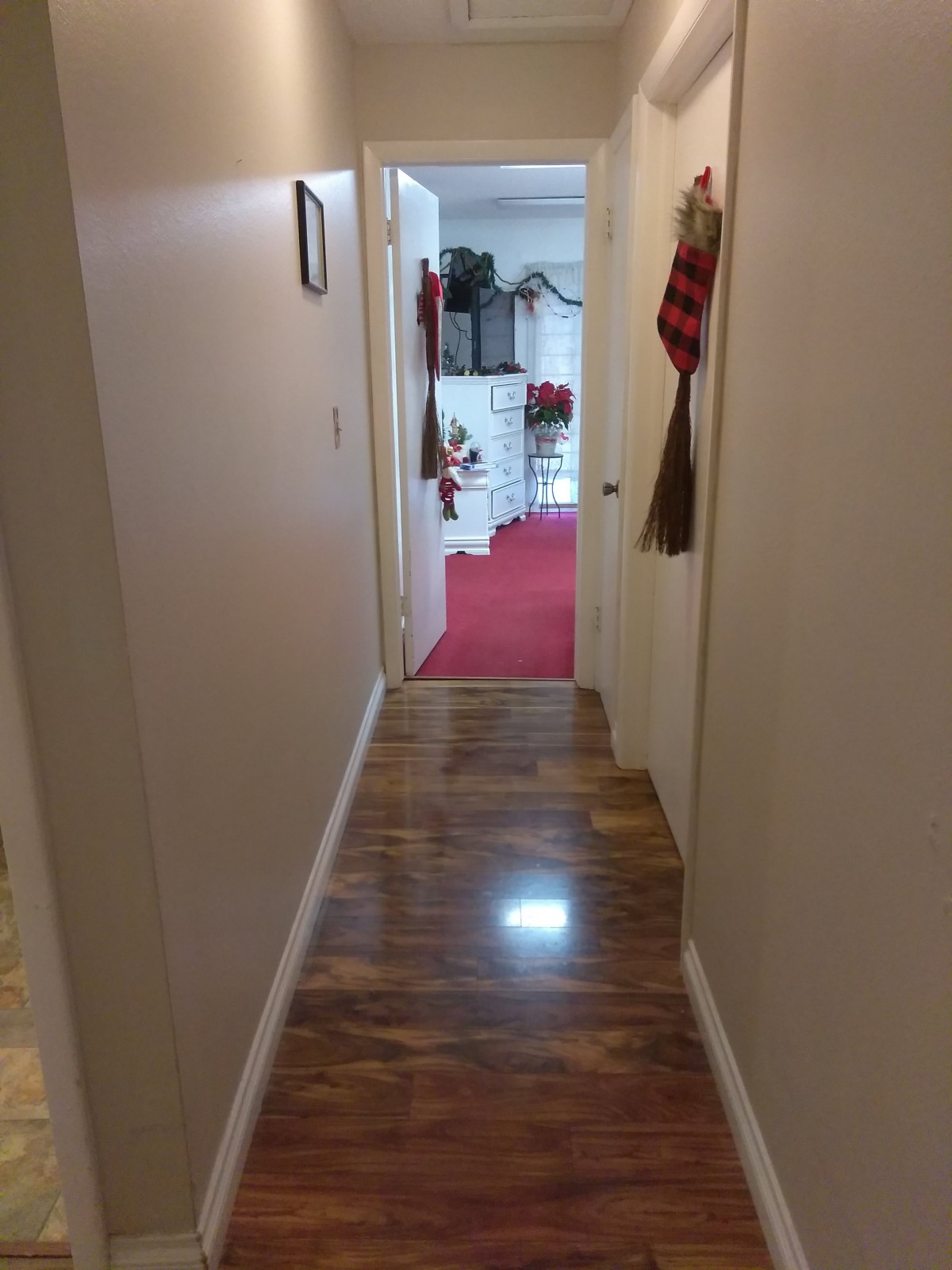 A cozy hallway with a wooden floor leading to a decorated room.
