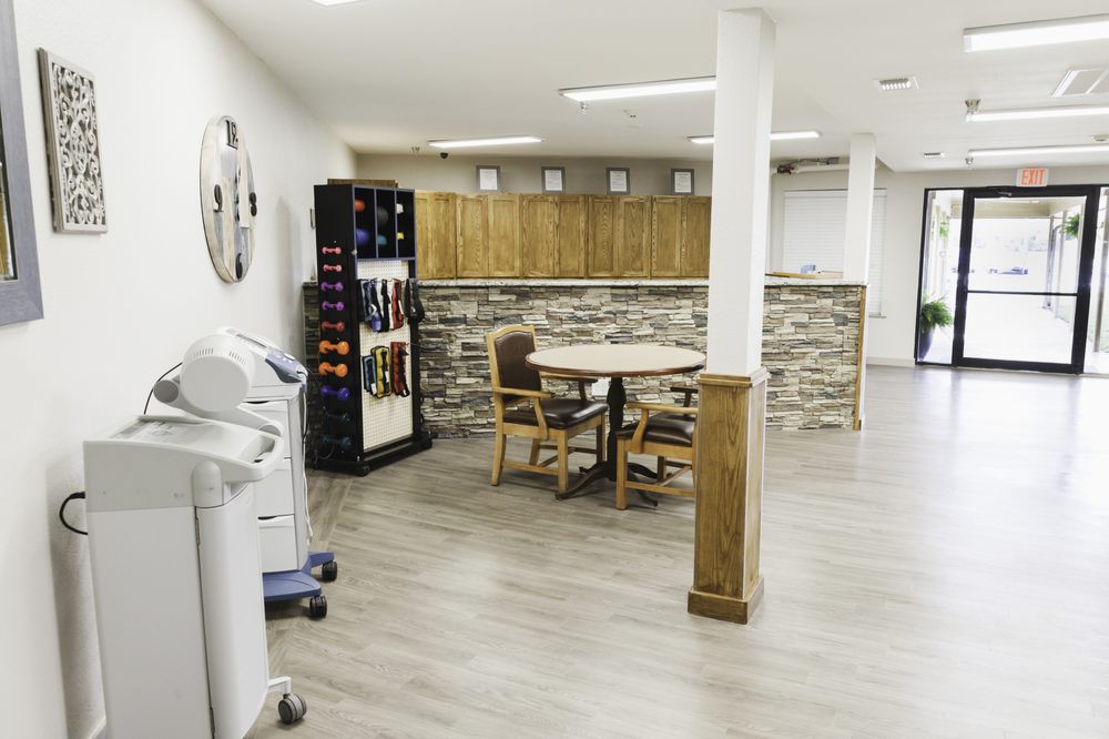 A modern, minimalist room featuring a wine rack and a small table with chairs on a hardwood floor.
