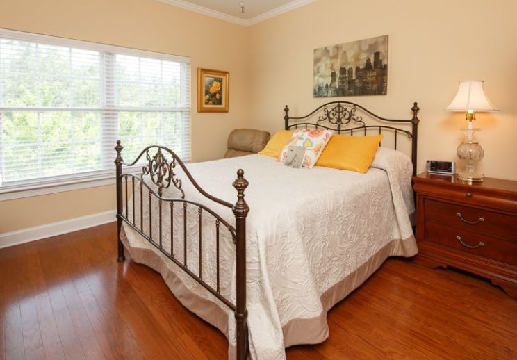 A cozy bedroom with an iron bedframe, white bedding, and yellow accent pillows.