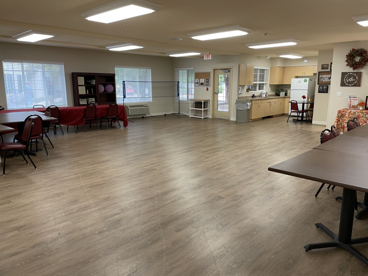 A spacious community center interior with an open floor plan and a kitchen area.