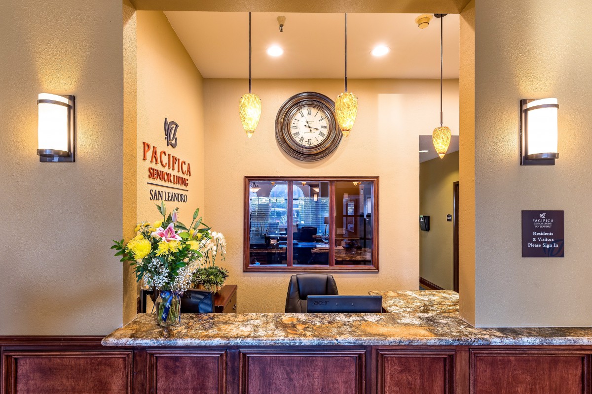 A welcoming reception desk with a clock and a bouquet of flowers.