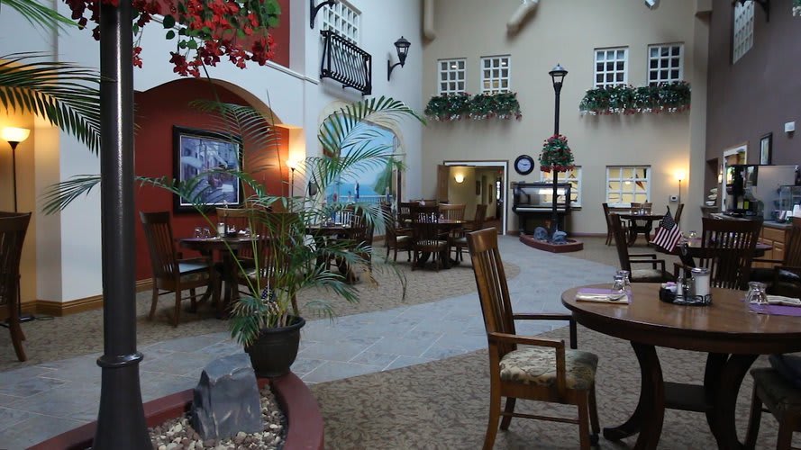 A cozy indoor dining area with tables and chairs, decorated with plants and artistic elements.