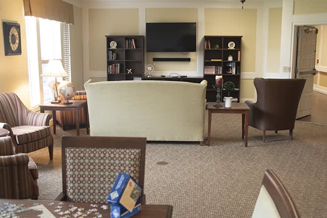 A cozy living room with a sofa, television, and bookshelves filled with various items.