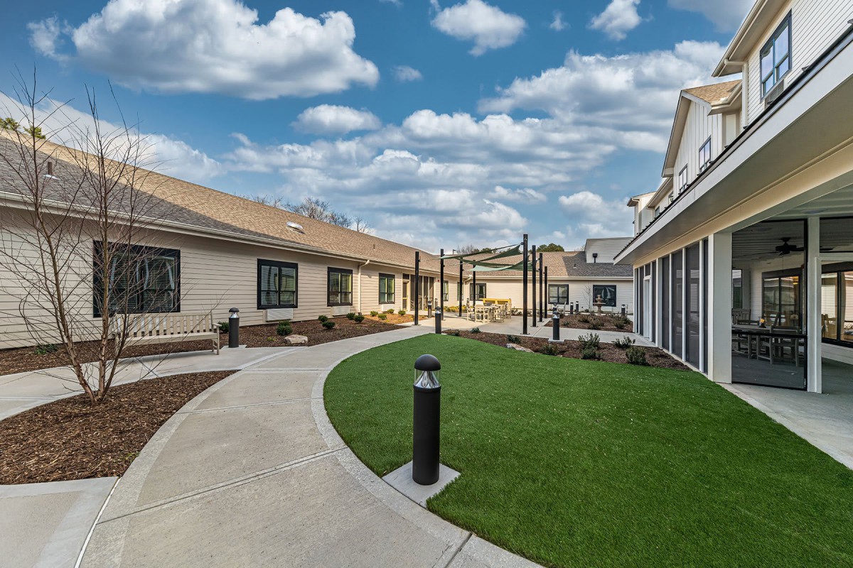 A well-maintained courtyard with a lawn and pathway between buildings under a cloudy sky.