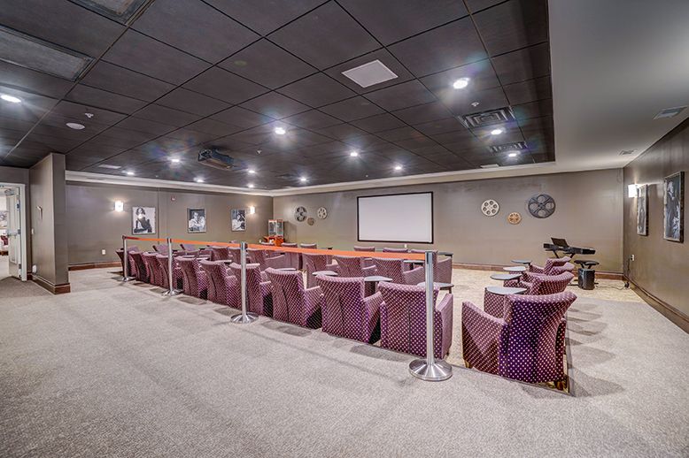 A well-lit theater room with rows of comfortable seating facing a large screen.
