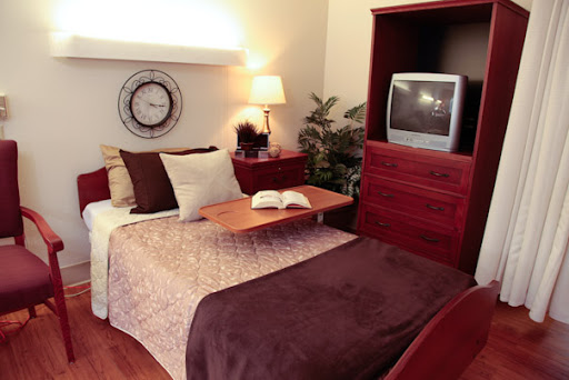 A cozy bedroom featuring a neatly arranged layout with a television, decorative pillows, and warm lighting.