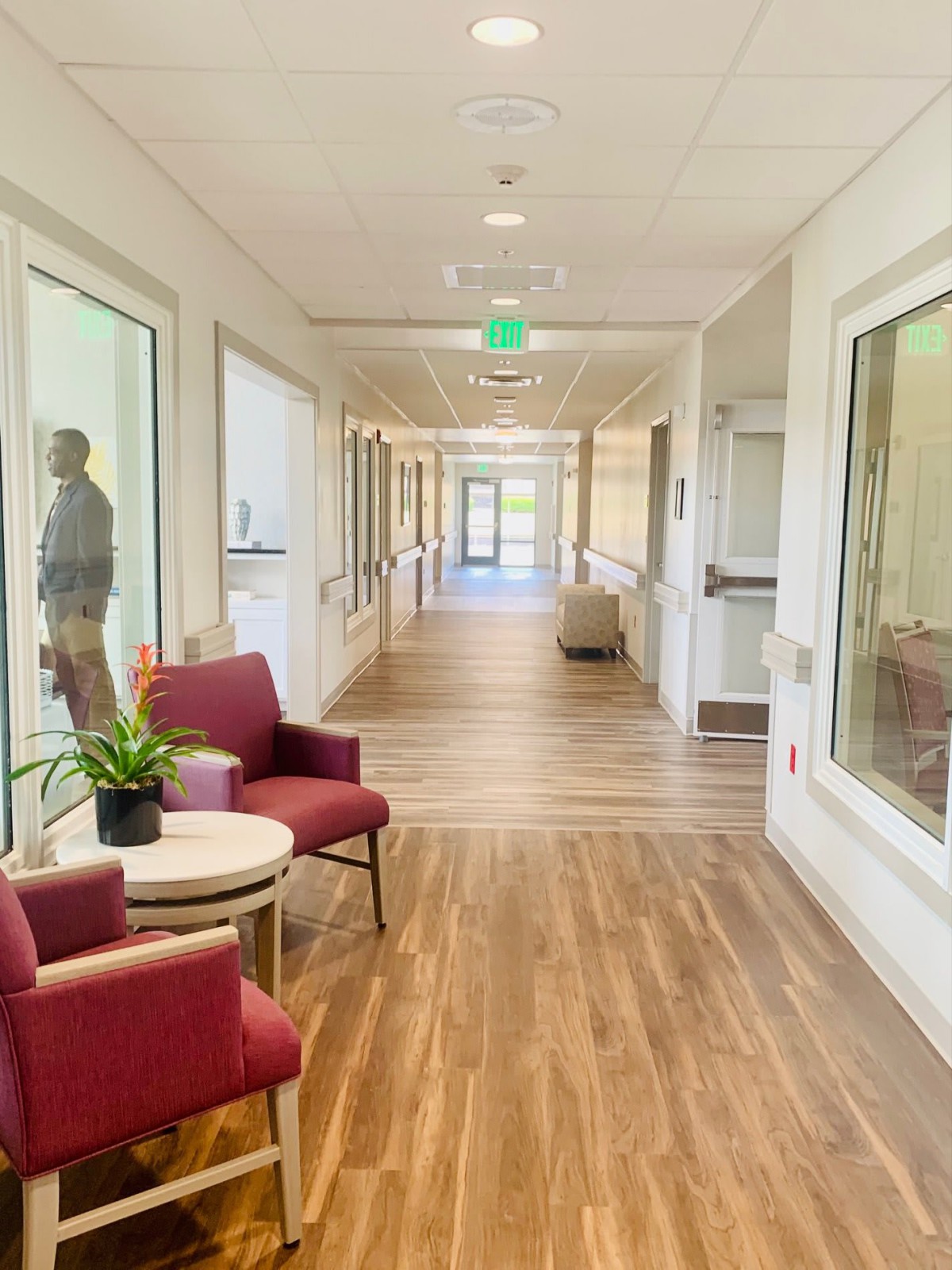 A brightly lit hallway with chairs and large windows.