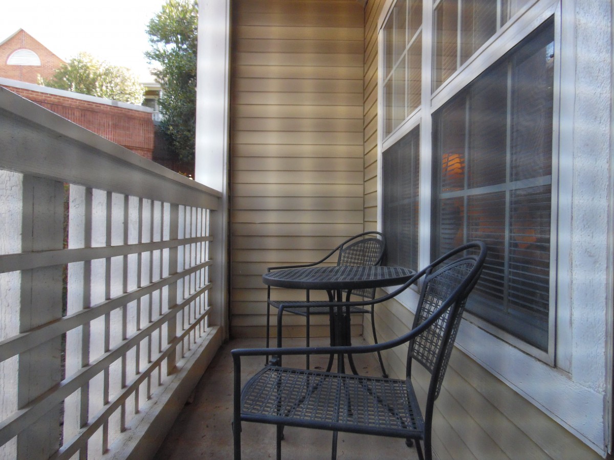 A small urban balcony featuring metal chairs and a table.