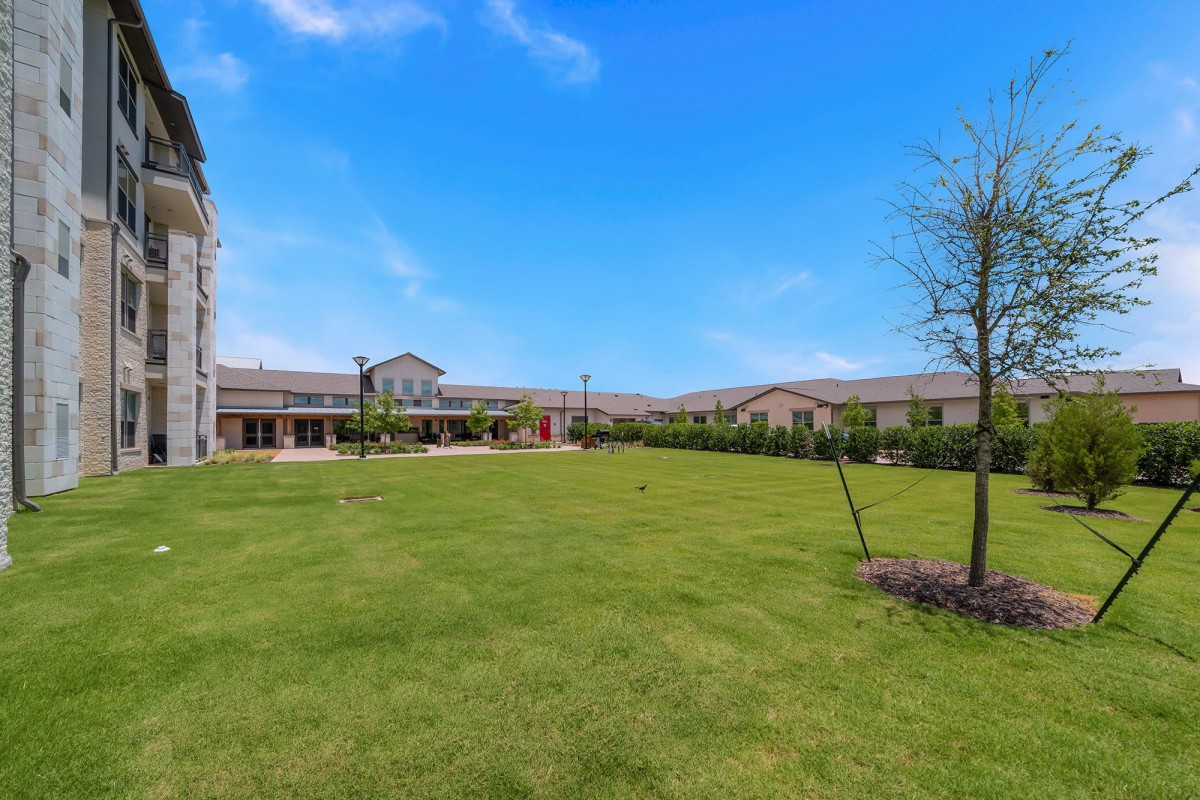 A spacious lawn in front of a large building under a clear blue sky.