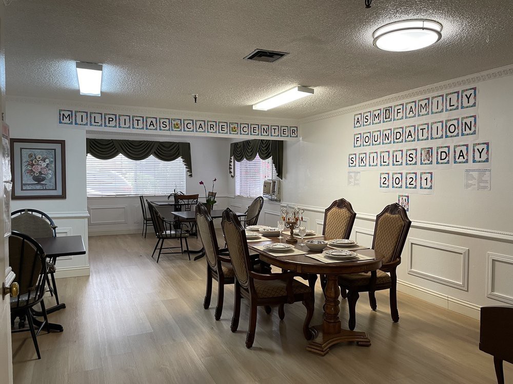 A well-decorated dining room with an elegant table setting and comfortable chairs, featuring wall art and draped curtains.