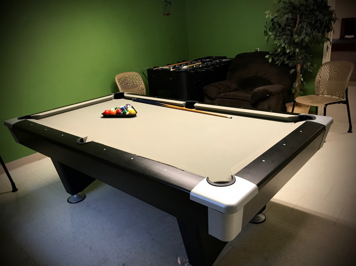 A pool table in a game room with a set of billiard balls arranged for play.