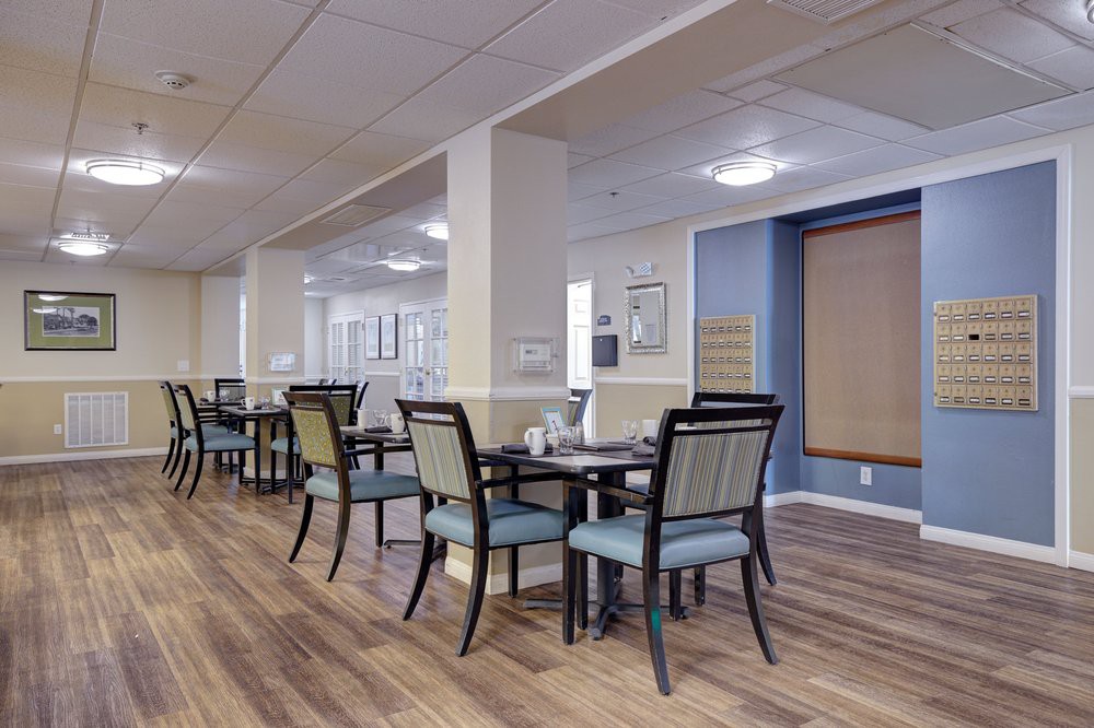 A modern dining area with neatly arranged tables and chairs, featuring wood flooring and contemporary decor.