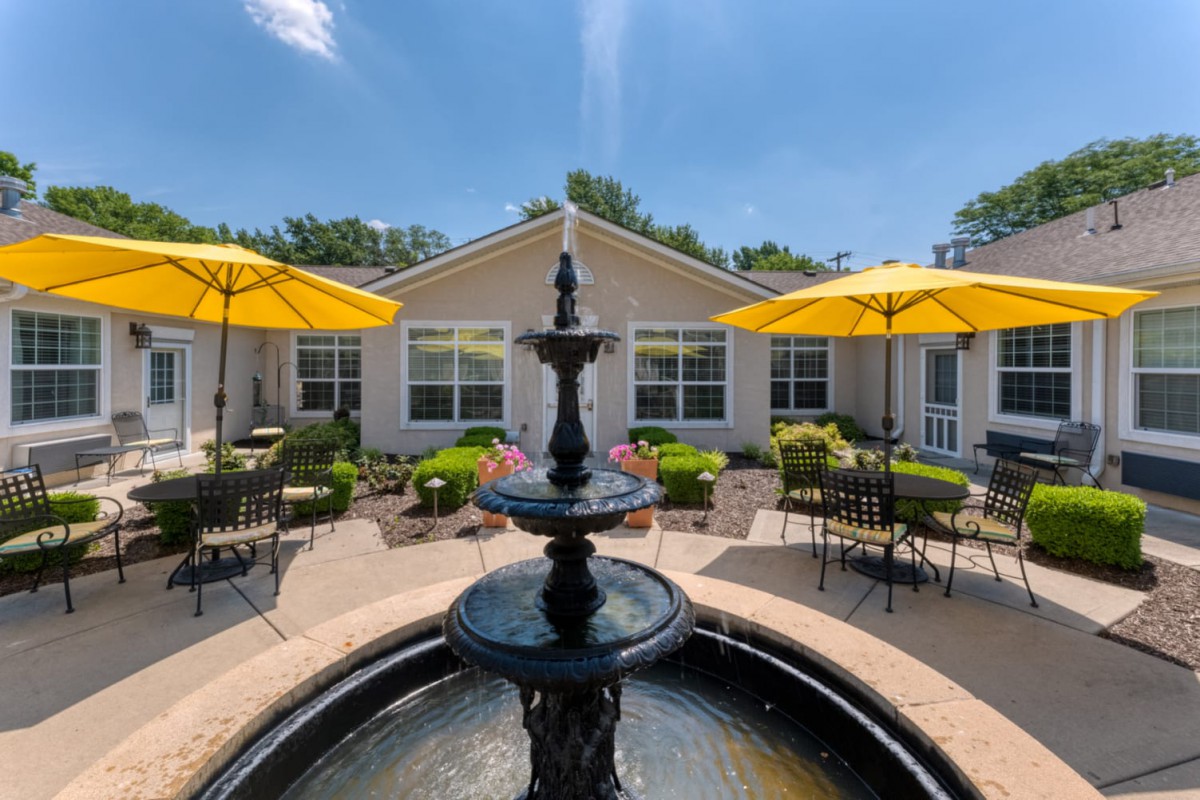A serene courtyard with a fountain and outdoor seating under yellow umbrellas.