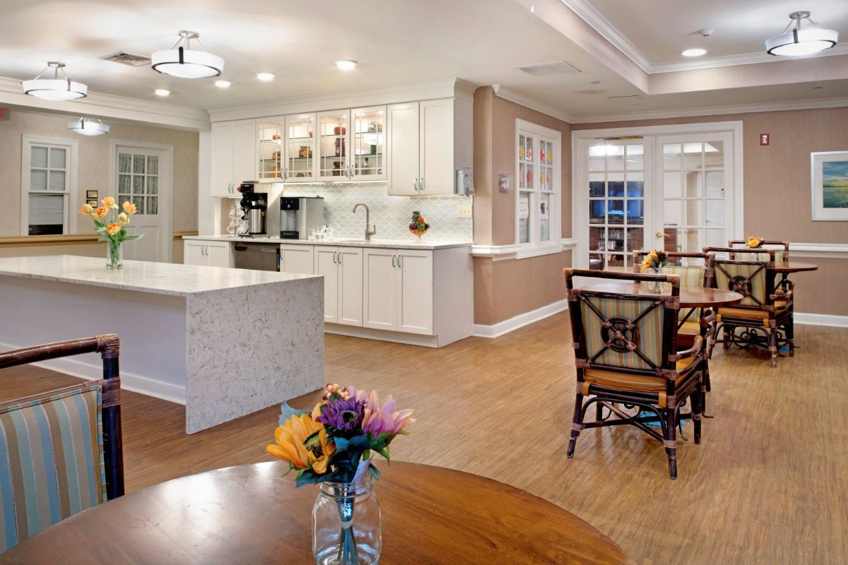 A modern open-concept kitchen and dining area with white cabinets, a large kitchen island, and hardwood floors.