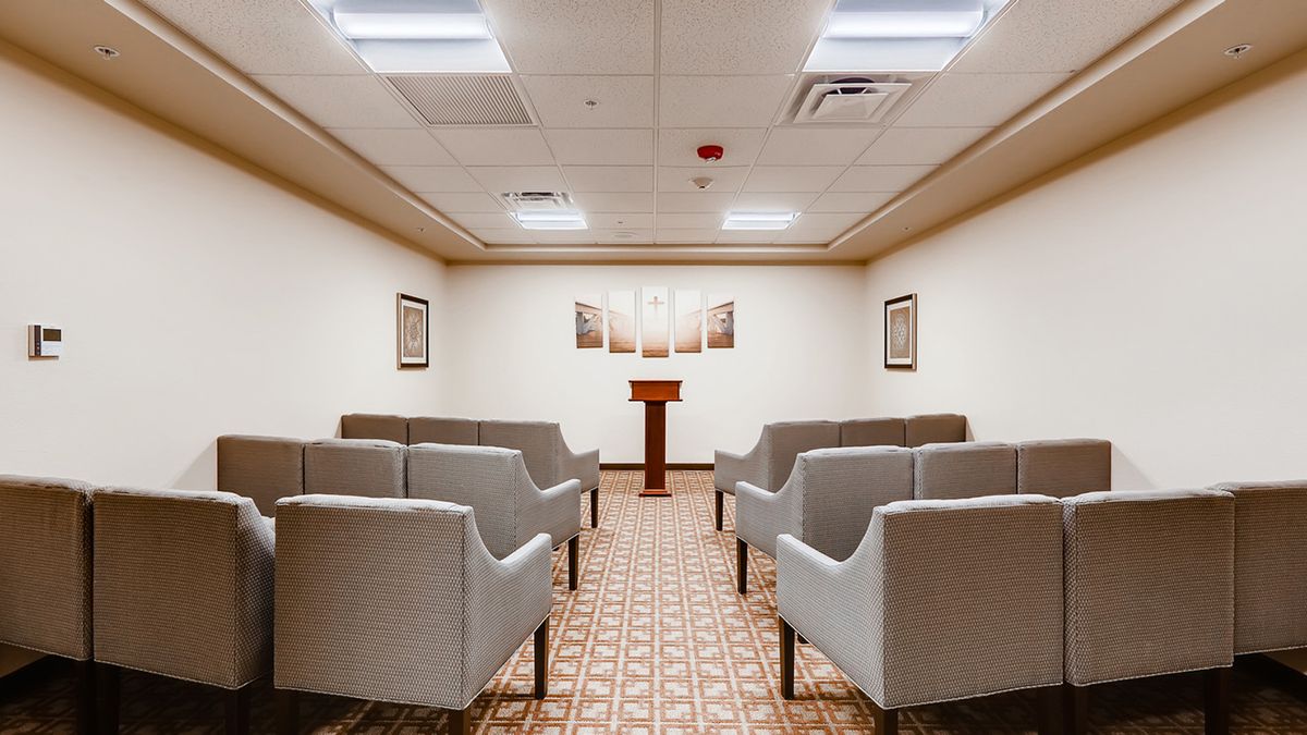 An empty conference room with rows of chairs facing a podium.