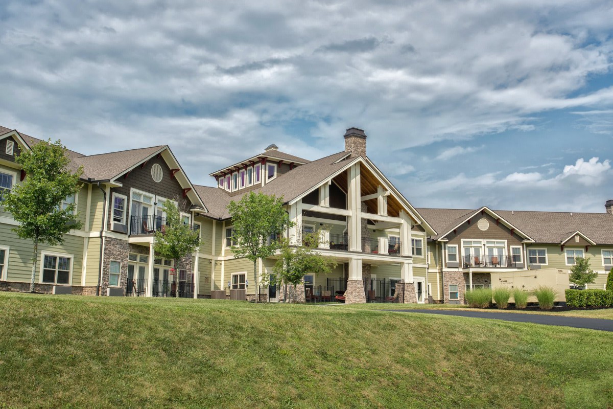 A large residential building set against a cloudy sky, surrounded by a well-maintained lawn.